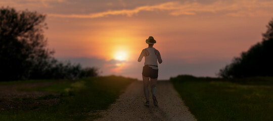 Young sportive girl ruining over green land nature at morning sunrise.