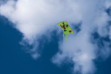 Colorful kite flying in blue sky with clouds