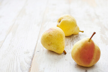 Three yellow pears on a white wooden table