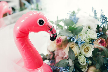 wedding rings lie next to a wedding bouquet and an inflatable toy in the form of a pink flamingo