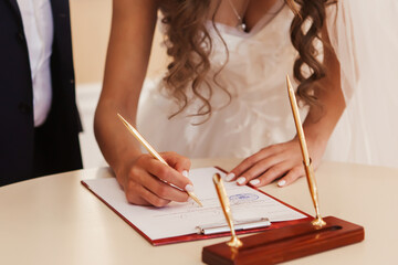 the bride fills out a document and signs at the wedding ceremony with a golden pen