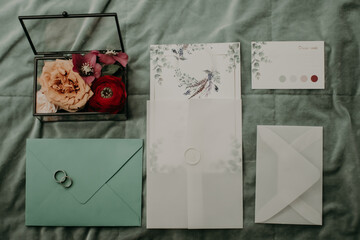 wedding rings lie on an envelope with invitation letters, dress code memos and a box with flowers