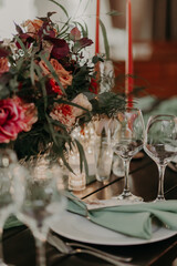 decor of a festive wedding table decorated with a large bouquet, lanterns and candles in green and red colors