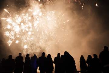silhouette of joyful people on the background of colorful fireworks with big explosions