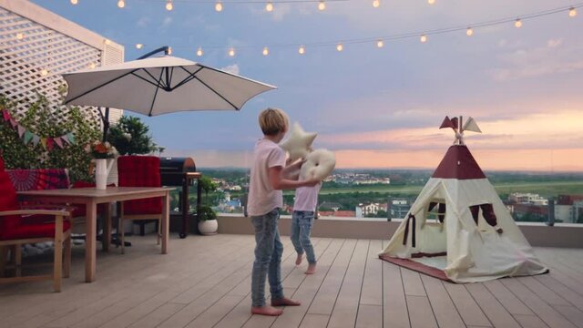 cute kids having fun, playing and fighting on rooftop patio during the sunset