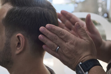 Fototapeta premium Barber does man hair styling after a haircut