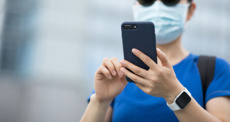 Woman wearing face mask using smart phone on city