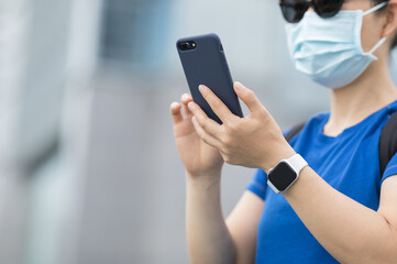 Woman wearing face mask using smart phone on city