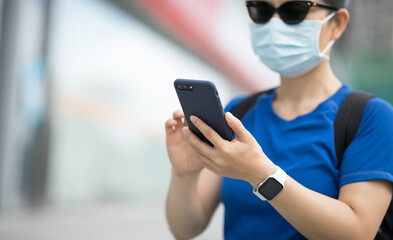 Woman wearing face mask using smart phone on city