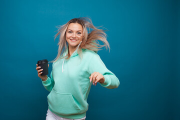 Happy girl smiling and drinking coffee, portrait in Studio on blue background.