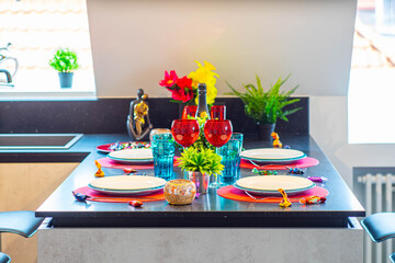 Close-up of the set table. Clean dishes and glasses. Bottle of wine. Decorative flowers. Modern interior.