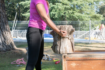 Caucasian woman holds a tree trunk that she uses in her sports routines. Healthy living and sports concept