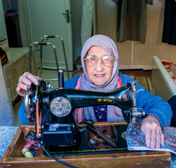 Arabic muslim old woman using old sewing machine