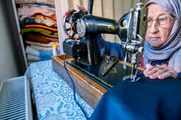 Arabic muslim old woman using old sewing machine