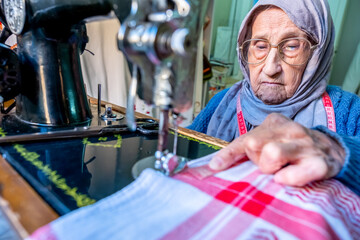 Arabic muslim old woman using old sewing machine
