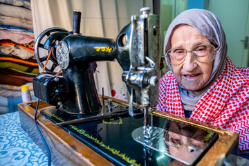 Arabic muslim old woman using old sewing machine