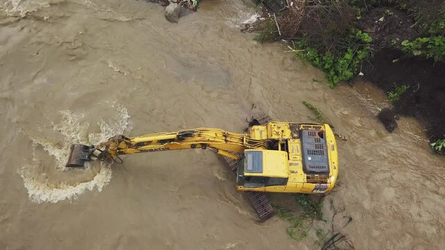 Yellow dredge Excavator working in the mountain river, scooping excavator bucket. Extracting gravel excavated in the river. Hydraulic works to strengthen the mountain road from floods.