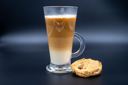 A studio shot of three-layered coffee drink and chocolate chip cookies in black grey background
