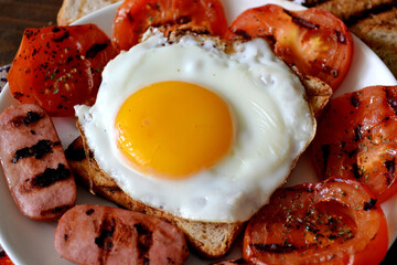fried egg with sausages, grilled bread and tomatoes with spices, background