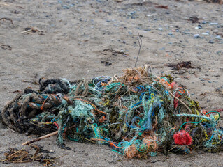 A colorful tangle rope washed up on a beach. The rope is frayed, worn and faded, and is the type used in the fishing industry. There is room for text above.