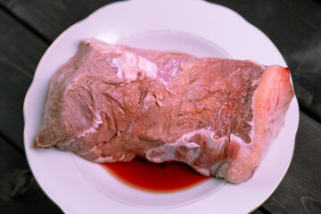 Raw meat in a plate on a wooden background