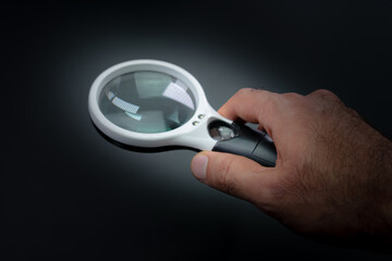 Hand holds a magnifier on a black background