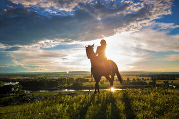 girl riding a stallion on a sunset background