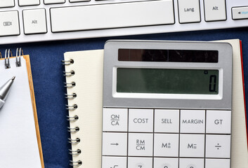 Close up white computer keyboard and calculator on yellow background. View from above.