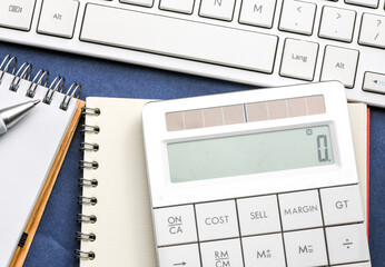Close up white computer keyboard and calculator on yellow background. View from above.