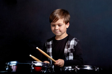 Fototapeta na wymiar A brunette child boy plays the drums. Studying in the studio.