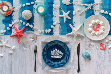 Columbus Day lunch table setting with nautical sea decorations on blue stripy runner, classic blue...