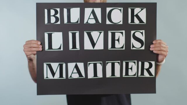 Close up hands man hold poster Black Lives Matter racial morality society peace human text words can kill torture close up slow motion