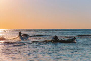 Fototapeta premium fishing at sunset,sea ​​adventures, jet ski, fishermen, spray of water, on the waves