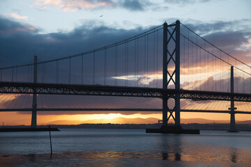 Two bridges against the setting sun and the sea, Forth Road Brtidge and Queensferry Crossing, Scotland, United Kingdom