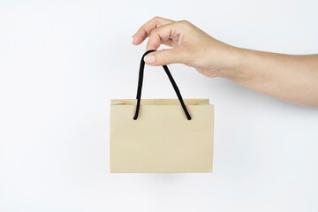 Small paper bag in a woman's hand on a light background, a woman holding a package because she is...