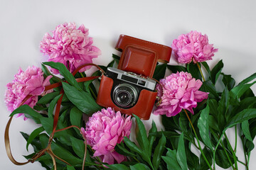 old black camera with pink peonies on the white background