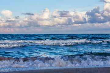 Sea waves, sandy beach and clouds