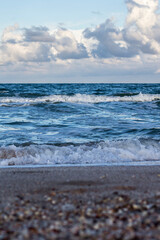 Sea waves, sandy beach and clouds