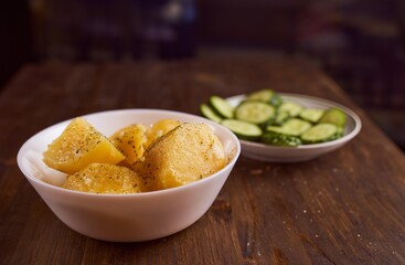 Boiled potatoes with mslom seasonings in a plate on a brown background