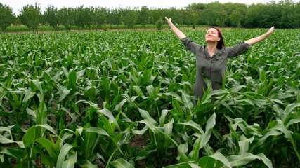 A woman in a field with her arms outstretched and her head raised to the sky with a smile and closed eyes. A female farmer enjoys her success.