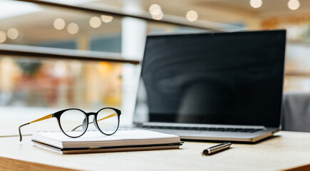 Glasses at the workplace in the office near the laptop and notepad. Business hours