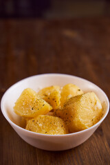Boiled potatoes with mslom seasonings in a plate on a brown background