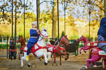 Fototapeta na wymiar Toddler having fun on vintage French merry-go-round in Paris