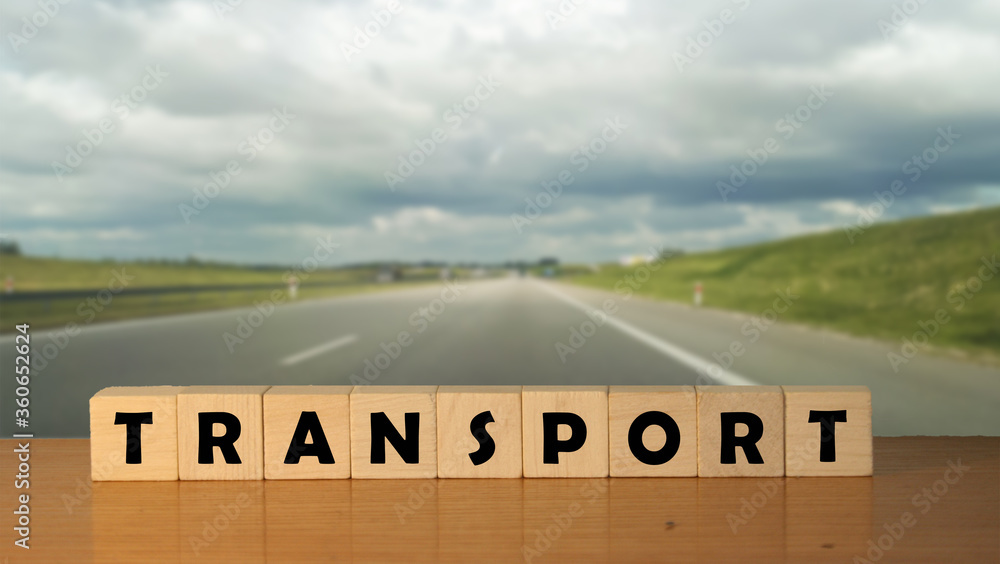 Poster transport concept message word on a wooden desk on cube blocks with a empty road background.