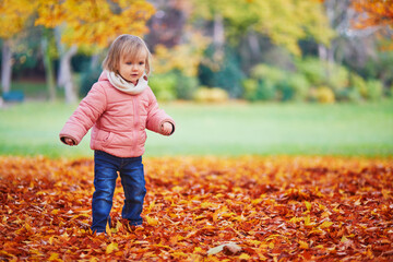 Adorable cheerful toddler girl running in Montsouris park in Paris