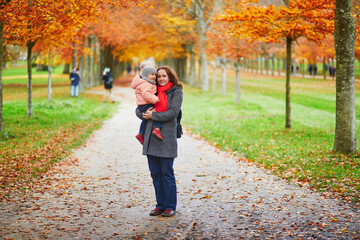 Happy smiling woman with toddler girl on fall day in park