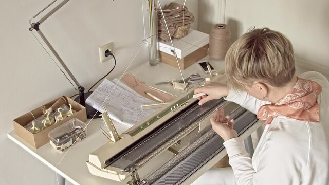 A woman works behind a knitting machine