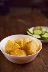 Boiled potatoes with mslom seasonings in a plate on a brown background
