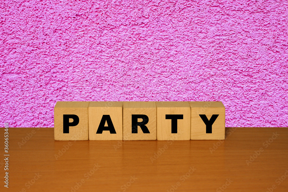 Poster party message sign on a wooden desk on cube blocks with a abstract pink background.