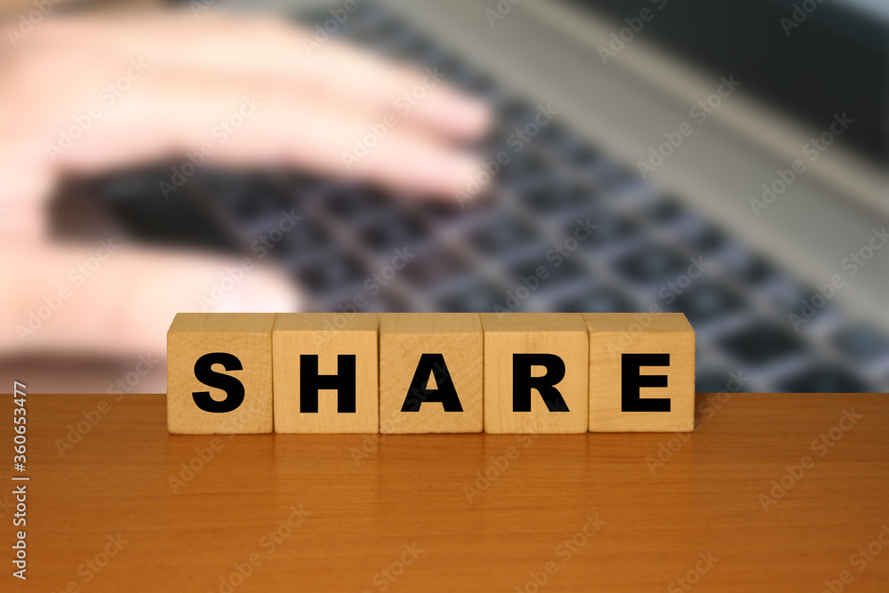 Aufkleber share message word on a wooden desk on cube blocks with a laptop keyboard background.